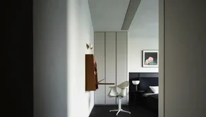 Modern minimalist bedroom with concrete floor, black furniture, and white elements.