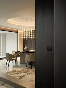 Modern dining room featuring a round table and chairs with marble flooring and a unique chandelier.