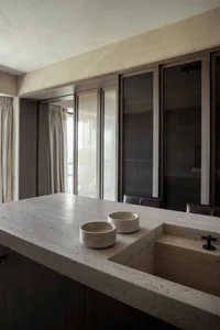 A modern kitchen interior with a concrete countertop featuring a built-in sink and two bowls.