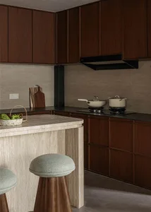 A modern kitchen featuring a marble countertop with wooden stools and stools.