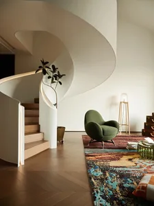 A modern living room featuring a plush carpet, metal furniture, and a cozy green armchair.