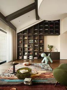 A modern living room featuring a large home library with bookshelves filled with books and decorative items, a cozy green arm