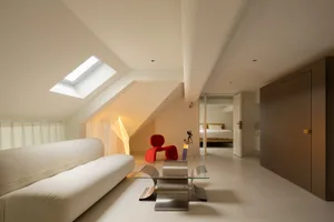 Modern living room with white furniture, minimalist design, and a red chair.