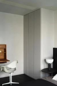 A minimalist bedroom featuring neutral-toned furniture and a contemporary interior design with integrated storage solutions.