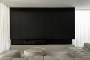 Modern minimalist living room with concrete walls and floors, featuring a large sofa and a stylish coffee table.