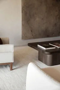 A modern minimalist living room featuring a wooden coffee table with two books on top.