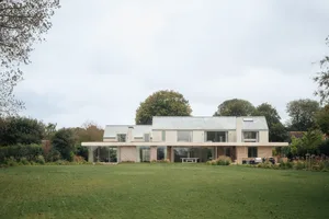 A modern residential house featuring glass walls and beige brick exterior.