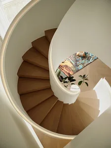 Staircase with wooden steps and a colorful rug at the bottom, viewed from above.