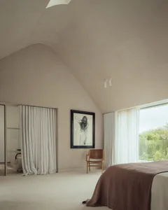 A minimalist bedroom featuring soft textiles, large windows, and a natural light-filled space.