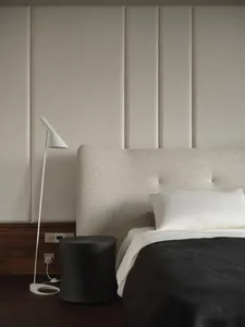 A minimalist bedroom with a white upholstered bed, white bedding, and a plain fabric headboard.