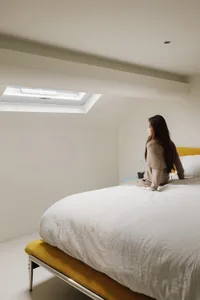 A minimalist bedroom with a white blanket and yellow bed
