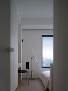 A minimalist bedroom with a wooden floor and a large window.