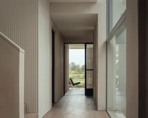 A minimalist interior with white walls and wooden flooring.