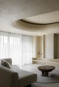 Modern minimalist living room with concrete walls, fabric sofa, and sheer curtains.