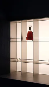 A modern bar display featuring a glass bottle on a grid-patterned shelf, backlit to highlight the drink.