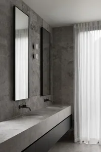 A modern bathroom with a concrete countertop, double sinks, and a large mirror.