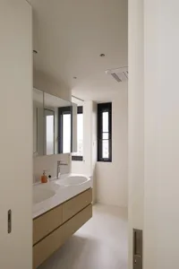 A minimalist modern bathroom featuring a sleek white vanity with concrete countertop and glass windows.