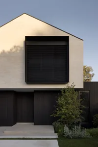 Modern house with brick exterior and wooden accents, featuring large windows with black shutters.