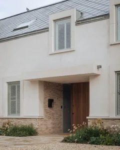Modern residential home with stucco exterior featuring a wooden door and greenery.