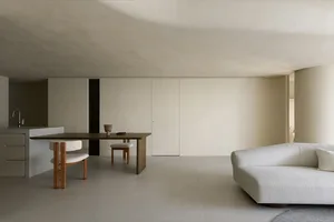 Minimalist modern interior design featuring sleek, concrete walls, wooden furniture, and fabric seating.