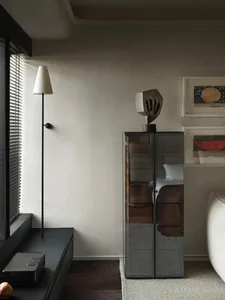 Modern living room featuring a glass cabinet with metallic sculptural object, wooden flooring, and minimalist decor.