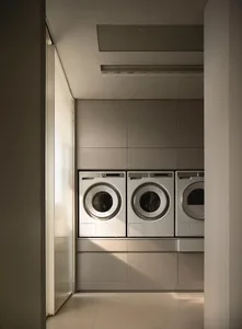 Modern metallic laundry room with white washing machines and gray cabinets.