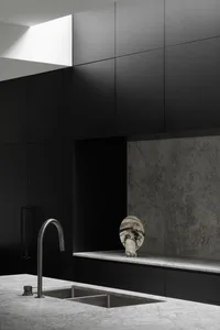 Modern minimalist kitchen featuring concrete countertops and marble backsplash