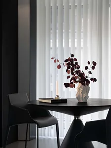 A modern office space featuring black furniture, a vase with red leaves, and a candle.