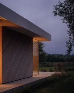 Modern residential exterior with wooden cladding and glass facade at dusk.
