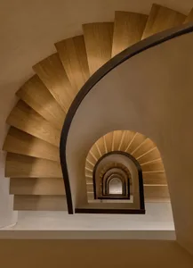 A modern, curved wooden staircase with a dark metal railing.
