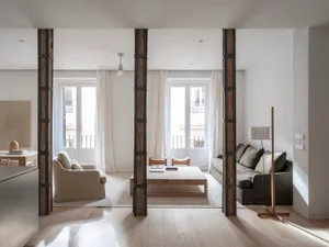 Modern minimalist living room with wood and concrete features, white furniture, and large windows.