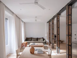A minimalist living room featuring wood furniture and a white wall.