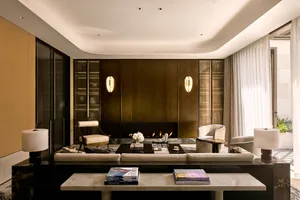 A modern living room with marble and glass materials, featuring a fireplace, sofa, armchairs, and coffee table.