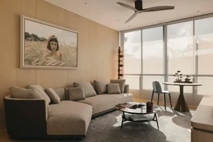 A modern living room features neutral-toned furnishings and wood paneling on the walls and ceiling. The space is furnished wi