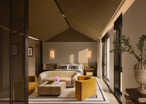 Modern minimalist bedroom with wooden walls and glass walls, featuring a white bed with black and white pillows, yellow armch
