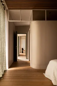 Modern minimalist bedroom with a wooden accent wall and natural light streaming through the window.