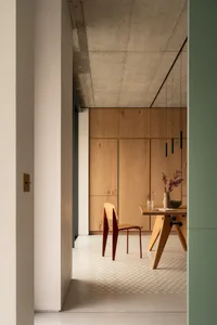 A minimalistic dining area with wooden elements and a concrete ceiling.