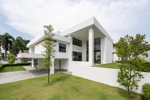Modern minimalist house with white concrete exterior and large windows.