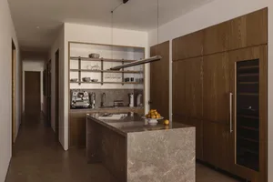 Modern kitchen featuring marble countertops, steel appliances, and wooden cabinetry