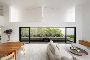 Modern minimalist living room with concrete flooring and large glass windows showcasing a garden view.