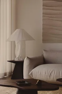 A minimalist living room with a neutral-toned fabric sofa, wooden coffee table, and patterned fabric pillows, all situated in