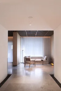 Modern minimalist living room with sandstone floor, white curtains, and white furniture.