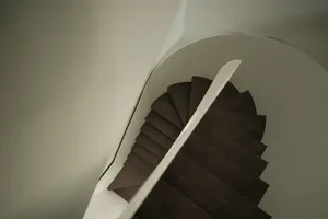 A modern dark wood staircase with white walls.