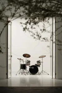 A modern drum set room with glass doors and black and silver drums.