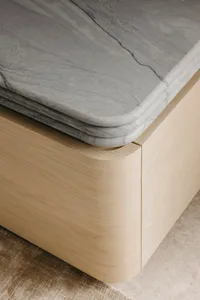 A modern interior space featuring a wooden bench with a marble top on a plush rug.