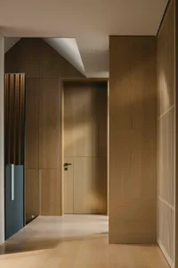 A modern interior designed with wooden paneling, featuring a door and a ceiling light.