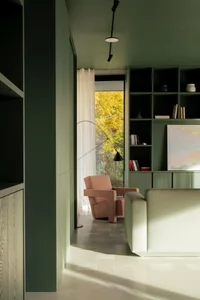 Modern living room featuring a comfortable couch, a cozy armchair, and an open bookshelf.