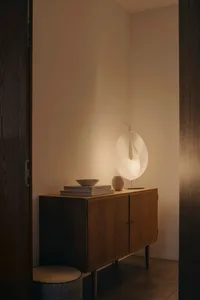 A modern living room featuring a wooden side cabinet with a paper lamp, books, and decorative objects.