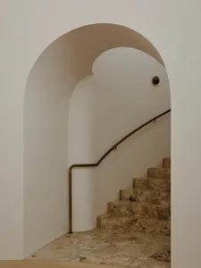 A modern marble staircase with curved walls and a bronze handrail.