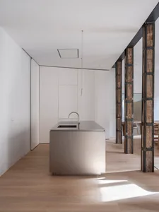 Modern, minimalist kitchen with a metal island.